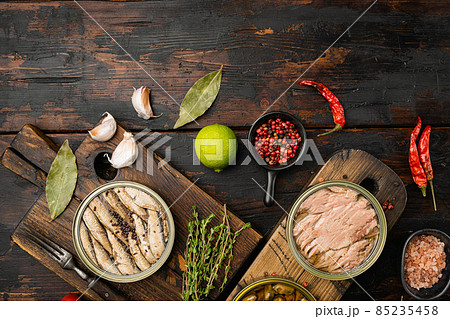 Various canned fish and seafood in a metal cans, on old dark wooden table background, top view flat lay, with copy space for text 85235458