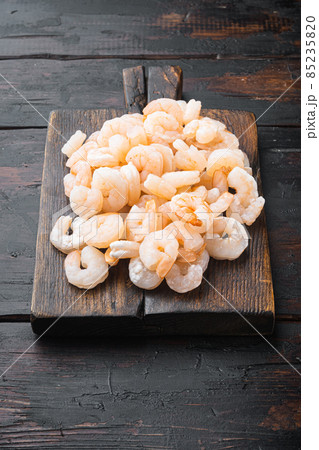 Boiled Peeled Shrimps, Prawns, on wooden serving board, on old dark wooden table 85235820