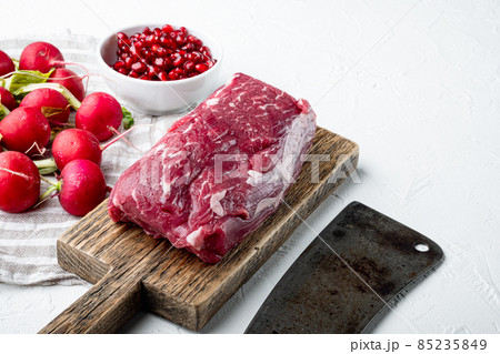 Raw beef fillet steaks with herbs and spices with whole tenderloin fillet cut, in cast iron frying pan, on white stone background, with copy space for text 85235849
