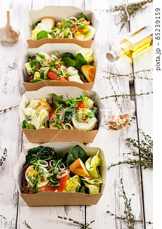 Delicious and healthy lunch with salmon fish fillet in a card box. Salad with smoked salmon, cheese, eggs, onion and vegetables. Seafood diet. Organic Mediterranean eat. Takeaway food. Vertical shot 85239159