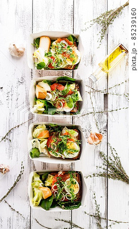 Delicious and healthy lunch with salmon fish fillet in a card box. Salad with smoked salmon, cheese, eggs, onion and vegetables. Seafood diet. Organic Mediterranean eat. Takeaway food. Vertical Banner 85239160