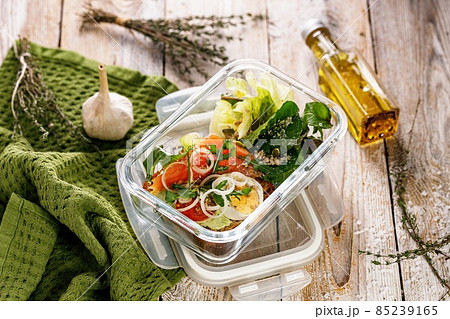 Delicious and healthy lunch with salmon fish fillet in a glass lunch box. Salad with smoked salmon, soft cheese, eggs, onion and vegetables. Seafood diet. Natural organic food Mediterranean lunch 85239165