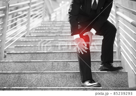 Businessman in a suit have the sore pain and painful knee problem expression and walk up and down on the stairway during go to office. Health care concept. Businessman in a suit have the sore pain and painful knee problem expression and walk up and down on the stairway during go to office. Health care concept. 85239293