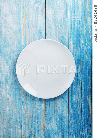 An empty round white plate on a blue wooden table. An empty round white plate on a blue wooden table. 85241439