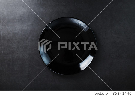 Black plate on a black background top view. Black plate on a black background top view. 85241440