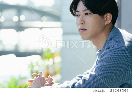 つまらなそうに外を見る若い男性 85243545