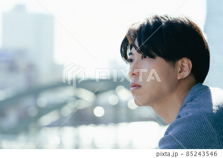 つまらなそうに外を見る若い男性 85243546