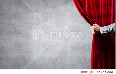 Concrete wall behind drapery curtain and hand opening it Concrete wall behind drapery curtain and hand opening it 85245288