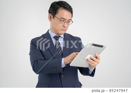 タブレットを持って真剣に操作する男性・白背景 85247947