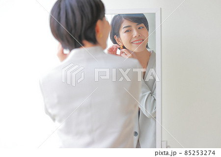 微笑んで鏡を見ながらイヤリングを付ける女性 微笑んで鏡を見ながらイヤリングを付ける女性 85253274