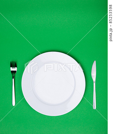 white plate, fork and knife on green background 85253598