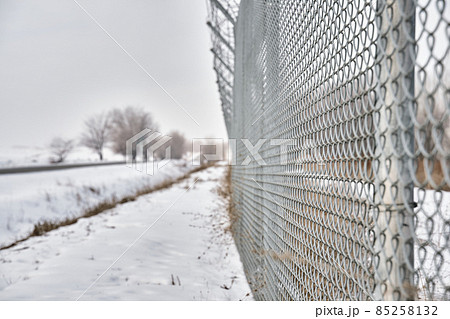 Close up of barbed wire fence on border in winter. Private secured object near highway. Maximum security detention facility. Closing for quarantine. Unauthorized entry is prohibited. Close up of barbed wire fence on border in winter. Private secured object near highway. Maximum security detention facility. Closing for quarantine. Unauthorized entry is prohibited. 85258132