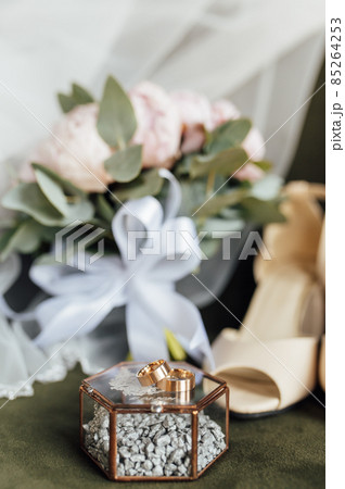 Wedding bouquet of white peonies, shoes and wedding rings on a wooden background 85264253