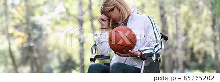 Disabled woman in wheelchair holding basketball ball and crying 85265202