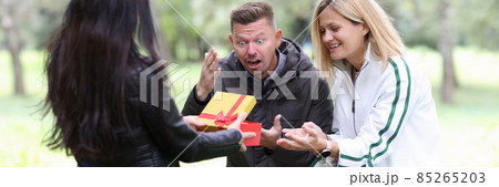 Woman giving gift in red box young couple in park 85265203