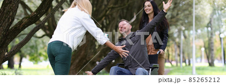 Disabled man in wheelchair walking in park with nurse and hugging his girlfriend Disabled man in wheelchair walking in park with nurse and hugging his girlfriend 85265212