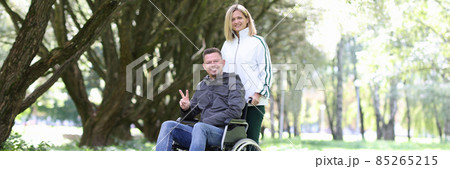 Woman walking in park with disabled man in wheelchair 85265215