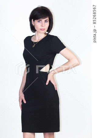 Slender woman 35-40 years old in a tight black dress with a cutout at the waist on a white background 85268567
