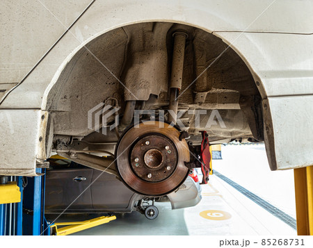 Damaged car and dirty disc brake lifting for maintenance in workshop 85268731