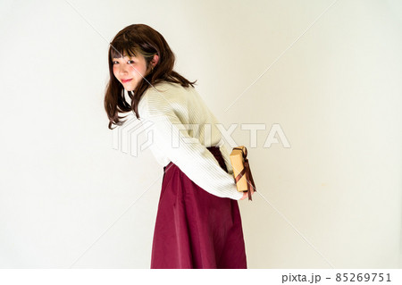 プレゼントを後ろ手に持って立っている女性 85269751