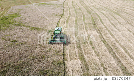 Aerial view of a combine harvester working in the field on a sunny evening. Industrial agriculture. Aerial view of a combine harvester working in the field on a sunny evening. Industrial agriculture. 85270847