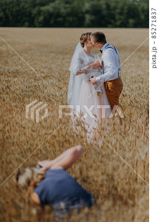 Bride and groom holding wedding champagne glasses on the background of wheat field. Happy wedding couple in wheat field. Beautiful bride in white dress and groom having fun on summer day. Just married Bride and groom holding wedding champagne glasses on the background of wheat field. Happy wedding couple in wheat field. Beautiful bride in white dress and groom having fun on summer day. Just married 85271837