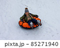 A child is tubing down the hill. Fun in the snow to ride down the hill on a tubing ice cheesecake. Earthly joyful fun, warm clothes. Boy is riding a tubing. Winter fun for children. High quality photo 85271940