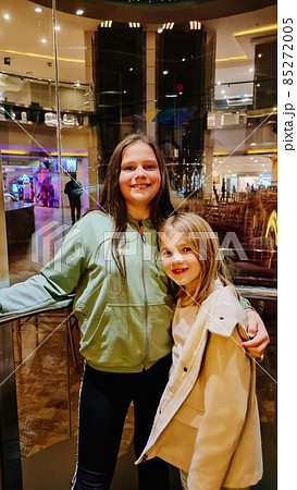 two cheerful girls in a glass elevator. rest in the hotel with children.  85272005