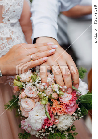 HONEYMOONS HANDS ON A WEDDING BOUQUET OF FLOWERS. Hands and rings on wedding bouquet 85273139
