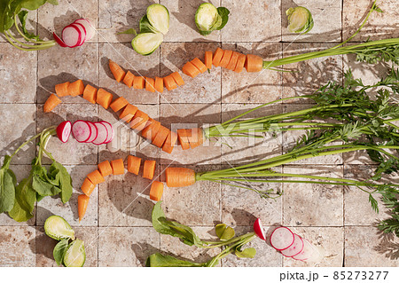 Bunch of carrot roots, Brussels sprouts and ripe radishes with green leaves on stone tales of earth tones top view. Healthy eating and dieting food concept. 85273277