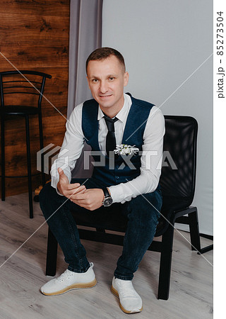 Morning of the groom. Groom morning preparation. Young and handsome groom getting dressed in a wedding shirt Morning of the groom. Groom morning preparation. Young and handsome groom getting dressed in a wedding shirt 85273504