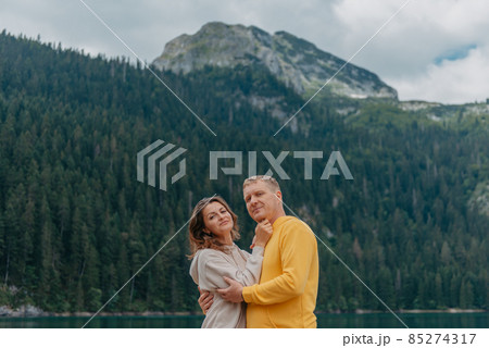 Romantic wedding couple in love standing on the stony shore of the lake, Scenic mountain view. The bride and groom. Beautiful caucasian couple hugging by the lake at summer sunny day. Honeymoon Romantic wedding couple in love standing on the stony shore of the lake, Scenic mountain view. The bride and groom. Beautiful caucasian couple hugging by the lake at summer sunny day. Honeymoon 85274317