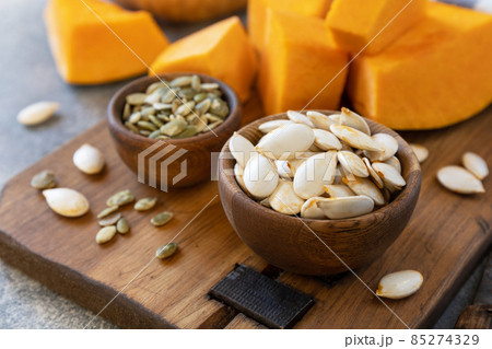 Raw superfoods pumpkin seeds after harvest. Pumpkin seeds in wooden bowl over gray stone background. 85274329