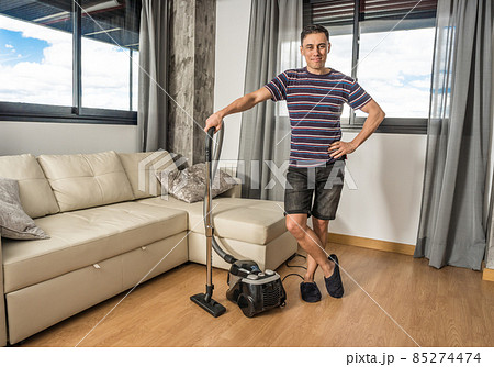 Smiling man vacuuming the living room. Household chores concept. Smiling man vacuuming the living room. Household chores concept. 85274474