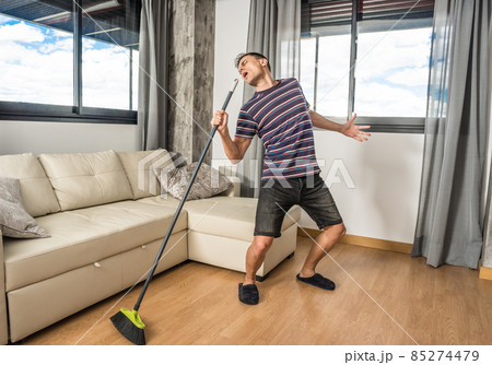 Singing man holding broom as if it were a microphone. Singing man holding broom as if it were a microphone. 85274479