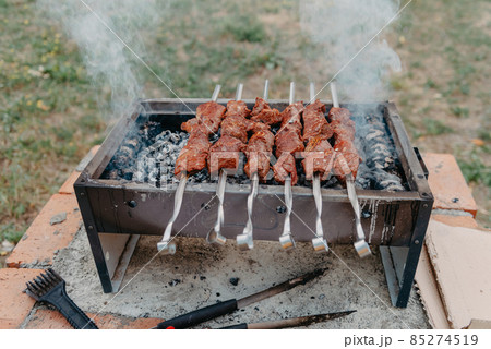 closeup of some meat skewers being grilled in a barbecue. 85274519