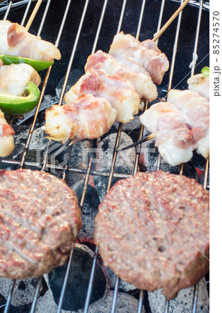 バーベキューコンロで焼かれているハンバーグと串刺しのアンコウのベーコン巻き バーベキューコンロで焼かれているハンバーグと串刺しのアンコウのベーコン巻き 85274570