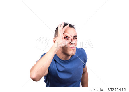 Man looking through a hole formed by his fingers Man looking through a hole formed by his fingers 85275456