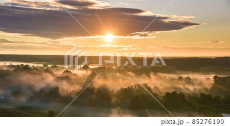 Sunrise of meadow with forest in sunlight and mist 85276190
