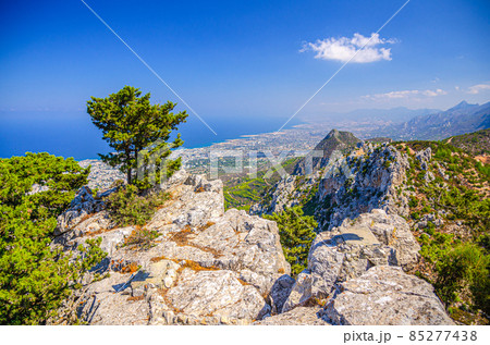 Aerial view of Kyrenia District valley with Kyrenia Girne city and Mediterranean sea in sunny day, green trees on rock of Kyrenia Girne mountains 85277438