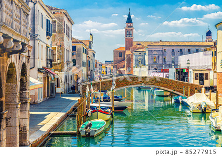 Chioggia cityscape with narrow water canal with moored multicolored boats, old buildings 85277915