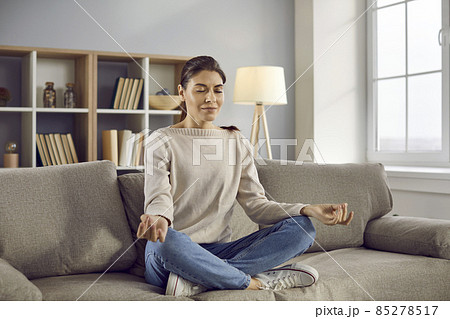 Calm millennial girl sit on sofa at home meditate practice yoga in mudra position. Relaxed young woman have meditation session indoors, relieve negative emotions breathe fresh air. Stress free. Calm millennial girl sit on sofa at home meditate practice yoga in mudra position. Relaxed young woman have meditation session indoors, relieve negative emotions breathe fresh air. Stress free. 85278517