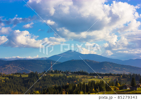 Beautiful mountain scenery with blue sky, white low clouds in a sky at sunny day in spring, summer or fall. A mountain top on a horizon and green coniferous forest. Ukrainian Carpathians landscape. Beautiful mountain scenery with blue sky, white low clouds in a sky at sunny day in spring, summer or fall. A mountain top on a horizon and green coniferous forest. Ukrainian Carpathians landscape. 85279343