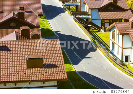 Aero view of brown tiled roofs with brick pipes of two-story houses paved street 85279344
