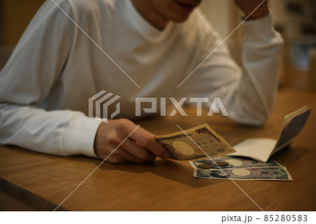 通帳を見ながら悩む男性 85280583