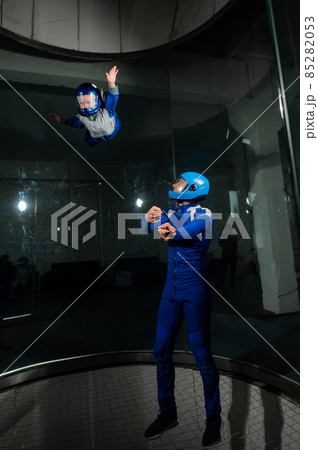 A man teaches a boy to fly in a wind tunnel. 85282053