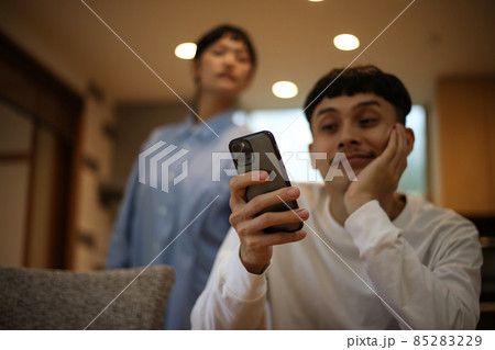 スマートフォンを操作する男性と怪しむ女性 85283229