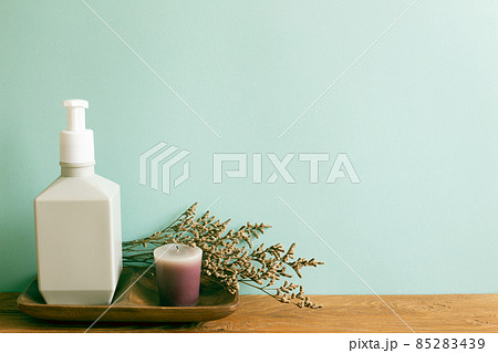 Spa beauty cosmetic bottle, aroma candle with dry flower on wooden shelf. mint wall background. home interior 85283439