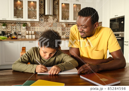 Happy young African man and his biracial son carrying out homework 85284598