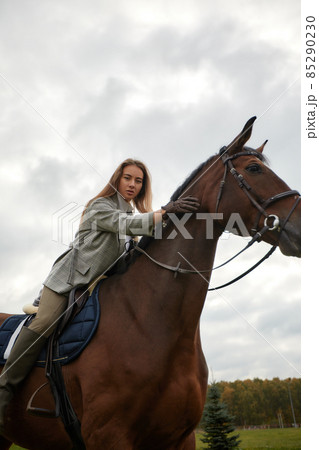 Beautiful young woman riding a horse on the field. Sideways to the camera. Freedom, joy, movement 85290230